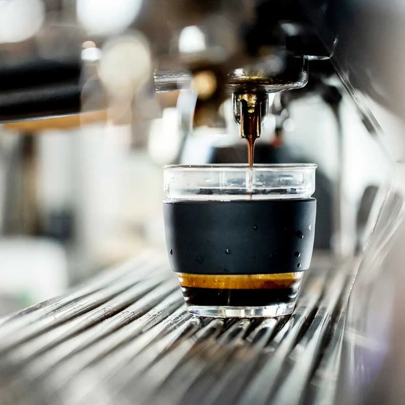 Espresso extracting into a glass cup on the coffee machine