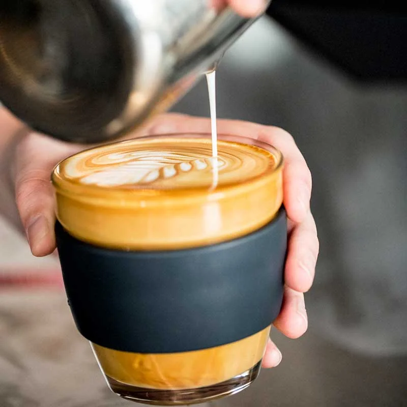 Milk being poured into a glass cup to make latte art